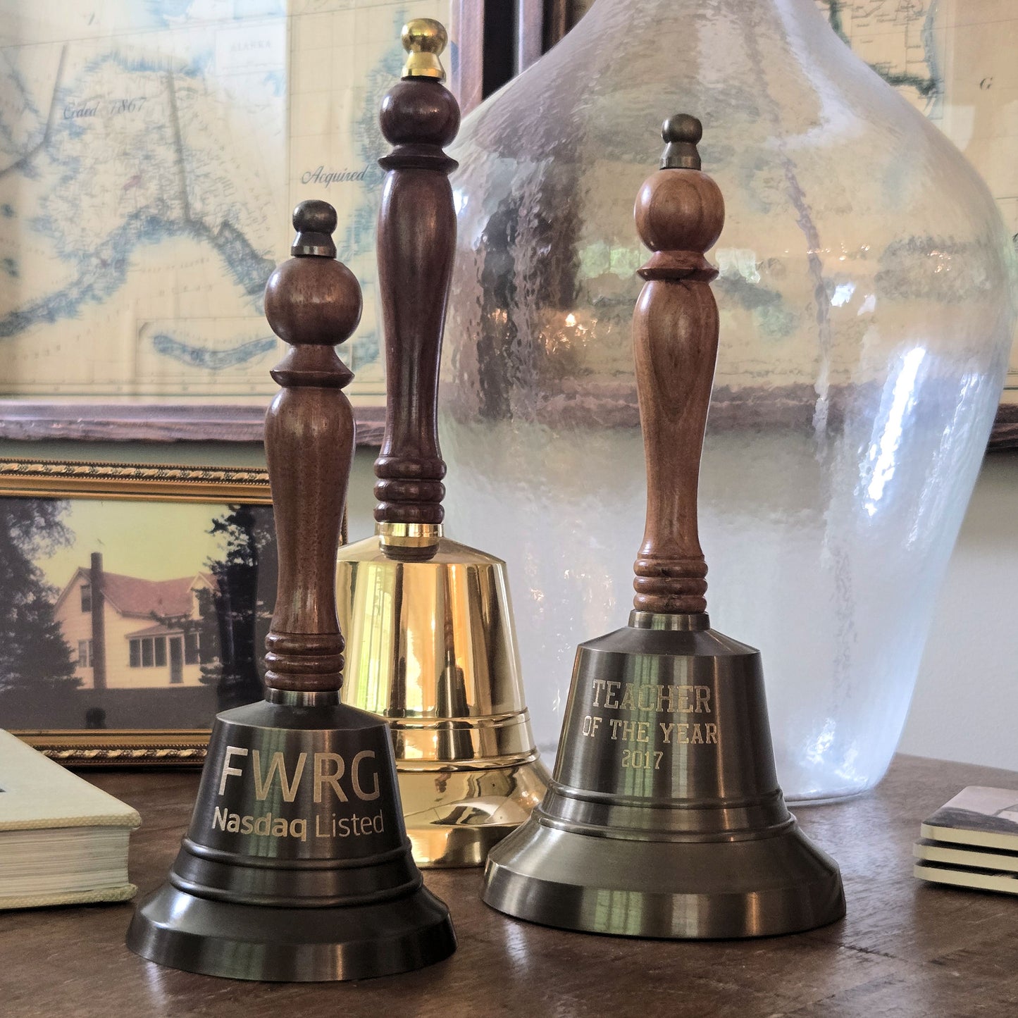 Three wooden bells with engraved text on a surface with a decorative background